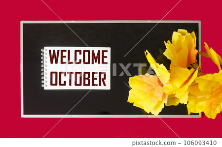 Note with welcome October text on notepad and black and red background with autumn decorations 106093410