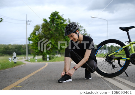 Cyclist in sportswear tying shoelaces, getting ready for riding. Active sporty, people and healthy lifestyle concept Cyclist in sportswear tying shoelaces, getting ready for riding. Active sporty, people and healthy lifestyle concept 106093461