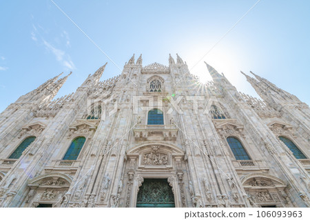 Milan Cathedral, Italian: Duomo di Milano, or Metropolitan Cathedral-Basilica of the Nativity of Saint Mary. View of main door and white marble facade on sunny summer day. Milan, Lombardy, Italy 106093963