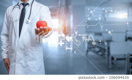 Doctor in lab coat holding red heart on hospital interior background 106094830