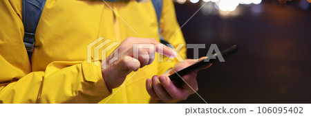 Close-up of male with backpack looking at his mobile phone outdoors. 106095402