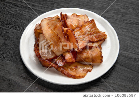 thinly sliced bacon fried in a frying pan 106095597