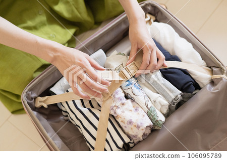 Women's hands and suitcases preparing for travel 106095789