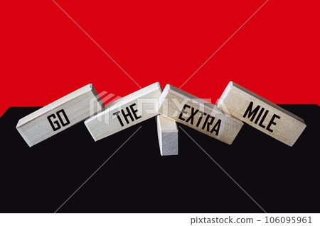 Wooden blocks with the inscription Go the extra mile on a black and red background.  106095961