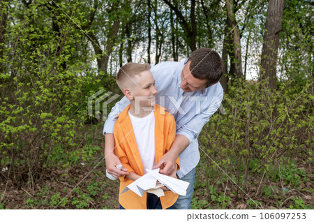 Cute child looks at dad holding paper airplanes Cute child looks at dad holding paper airplanes 106097253