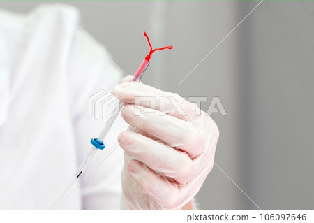 Gynecologist holding an IUD birth control device 106097646
