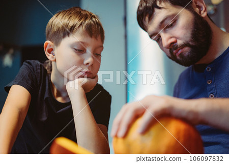 caucasian man with child carving a traditional Jack lantern from pumpkin. Halloween concept. Image with selective focus 106097832