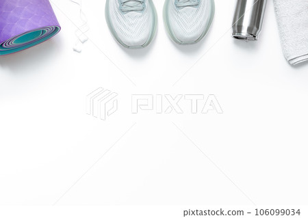 New light blue green female running shoes headphones metal water bottle towel and rolled yoga mat on emty white background. Stylish monochrome shoes for active people that incorporate new health 106099034