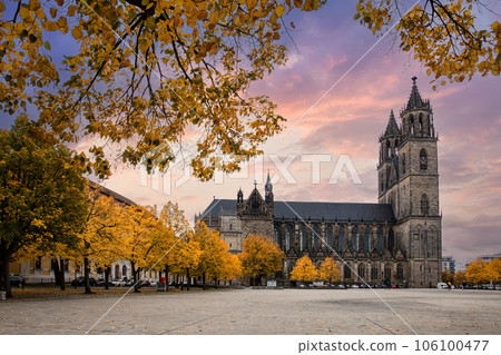 Scenic view of old ancient Magdeburger Dom cathedral at Dom square in Magdeburg old city center in bright orange autumn trees foliage in dramatic sunset sky. Germany tourism and travel destiantion 106100477