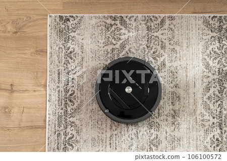 Top view of a black robotic vacuum cleaner that cleans the carpet Top view of a black robotic vacuum cleaner that cleans the carpet 106100572