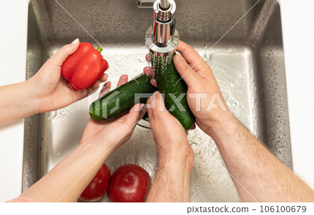 woman helping man wash ripe vegetables for salad woman helping man wash ripe vegetables for salad 106100679