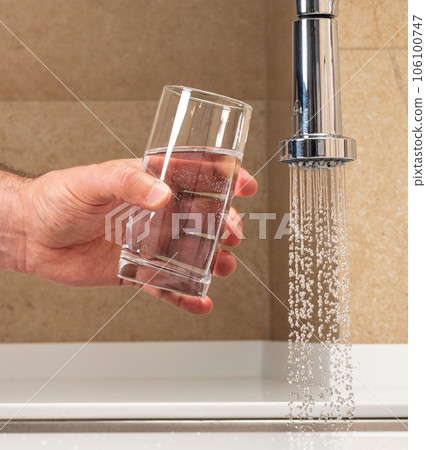 man getting a glass of water from a faucet 106100747