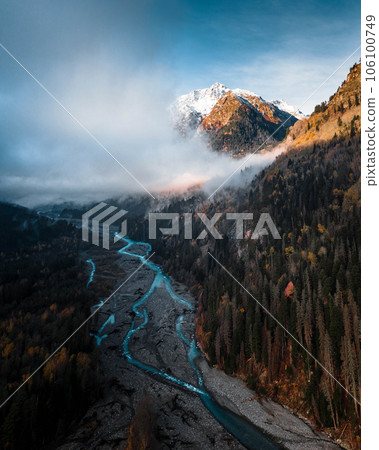 wild mountain river flows between trees under low clouds 106100749