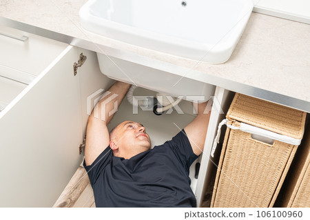 top view of repairing plumbing by a man under the sink 106100960
