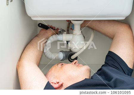 do-it-yourself plumbing repair by a man under the sink 106101095