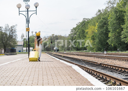 Going out into the world: a girl in a stylish outfit and glasses feels delight from the approaching journey. A young woman in yellow clothing and blue glasses is ready for an exciting journey. 106101667