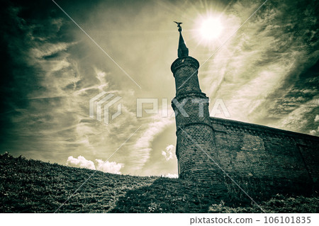 A fragment of an old fortress wall against the background of the sky with the sun and clouds A fragment of an old fortress wall against the background of the sky with the sun and clouds 106101835