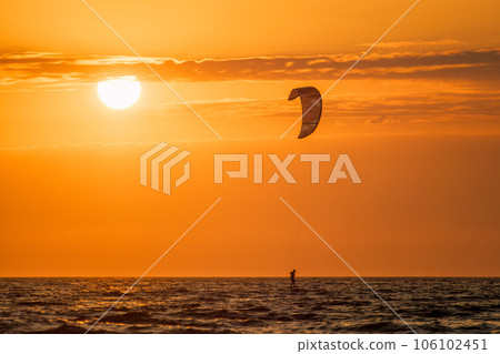 Foiling kiteboarding kitesurfing kiteboarder (kitesurfer) silhouette in the Atlantic ocean on sunset. Fonte da Telha beach, Costa da Caparica, Portugal 106102451