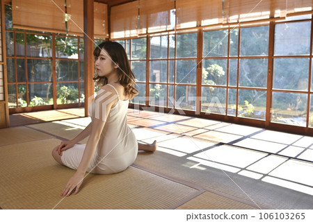 一個穿著吊帶背心的年輕女子坐在榻榻米上微笑 106103265