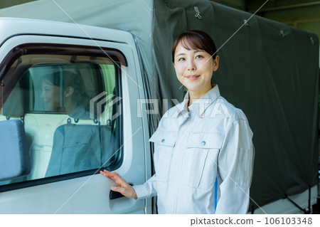 一名穿著工作服的女士站在卡車前 一名穿著工作服的女士站在卡車前 106103348