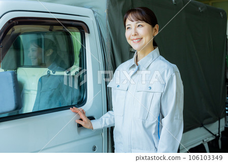 一名穿著工作服的女士站在卡車前 106103349