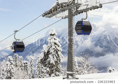 New modern spacious big cabin ski lift gondola against snowcapped forest tree and mountain peaks covered in snow landscape in luxury winter alpine resort. Winter leisure sports, recreation and travel 106103963