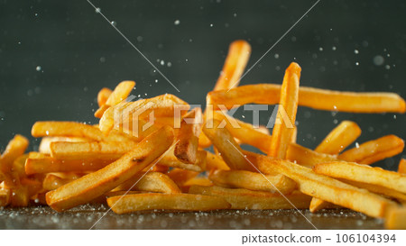 Freeze motion of flying french fries on dark background. Concept of junk unhealthy food, studio shot. Freeze motion of flying french fries on dark background. Concept of junk unhealthy food, studio shot. 106104394