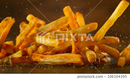 Freeze motion of flying french fries on dark background. Concept of junk unhealthy food, studio shot. 106104395