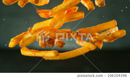 Freeze motion of flying french fries on dark background. Concept of junk unhealthy food, studio shot. Freeze motion of flying french fries on dark background. Concept of junk unhealthy food, studio shot. 106104396