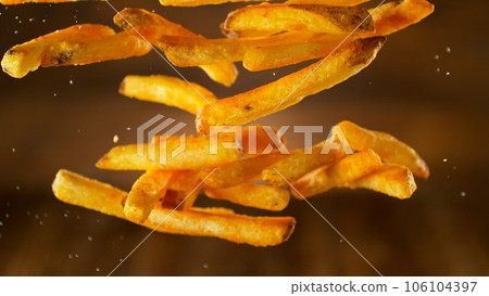 Freeze motion of flying french fries on dark background. Concept of junk unhealthy food, studio shot. Freeze motion of flying french fries on dark background. Concept of junk unhealthy food, studio shot. 106104397