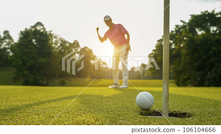 Golfer putting ball on the green golf, lens flare on sun set evening time. 106104666