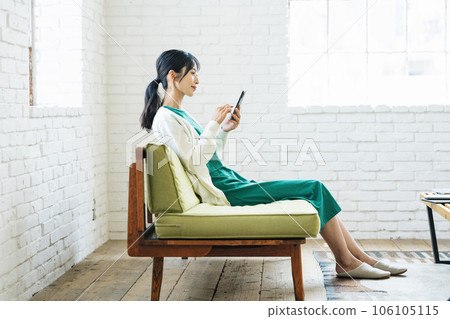 Woman watching smartphone on sofa Woman watching smartphone on sofa 106105115