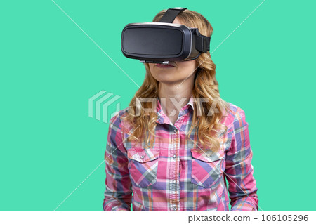 Portrait of a young woman enjoying vr experience. Isolated on green background. 106105296