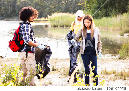 Young multi ethnic group of volunteers cleaning up the forest together, they are collecting trash 106106056