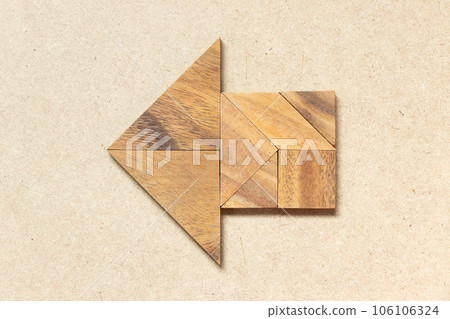 Wooden tangram in arrow shape on wood background 106106324