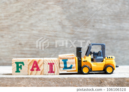 Toy forklift hold letter block l to complete word fail on wood background Toy forklift hold letter block l to complete word fail on wood background 106106328