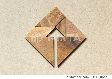 Tangram puzzle as arrow in square shape on wooden background (Concept for business direction and decision) 106106440