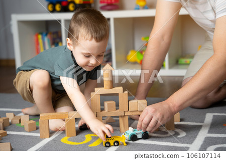 Little toddler boy 2,5 years playing wooden blocks and toy cars with dad. Spending time with children. Educational activities for kids. Children's room. Indoors Little toddler boy 2,5 years playing wooden blocks and toy cars with dad. Spending time with children. Educational activities for kids. Children's room. Indoors 106107114