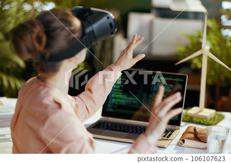 Seen from behind modern female with laptop and vr gear 106107623