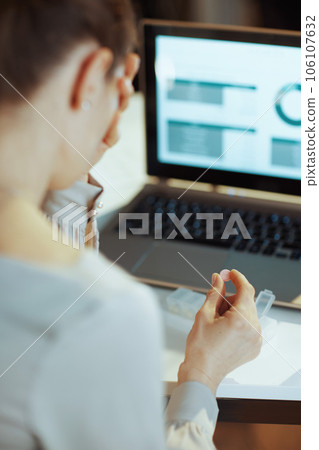 Seen from behind modern female with laptop having headache Seen from behind modern female with laptop having headache 106107632