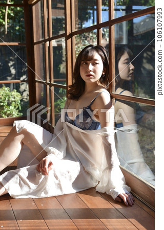 一位穿著內衣的年輕女子在一棟老私人住宅的門廊上放鬆 106107993
