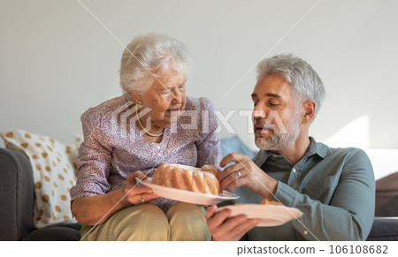 Senior mother giving her adult son fresh baked bundt cake. 106108682