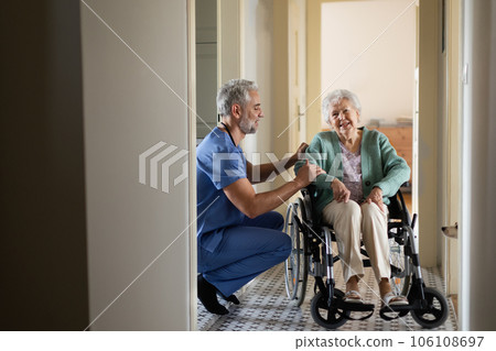 Caregiver doing regular check-up of senior woman in her home. 106108697