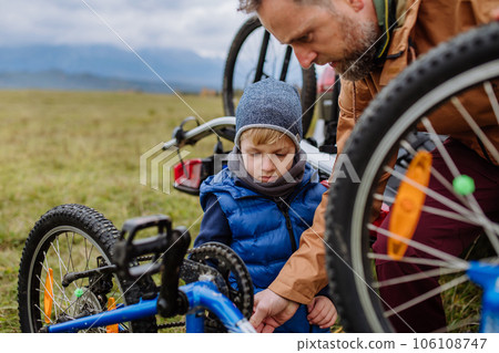 Littlle boy helping father attache a bicycle on bike carrier. 106108747