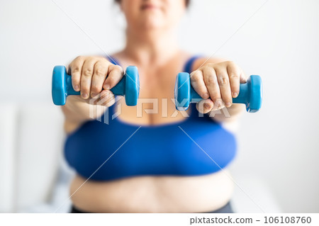 Close-up view of fat woman holding dumbbells. Woman diet weight loss overweight problem concept. Close-up view of fat woman holding dumbbells. Woman diet weight loss overweight problem concept. 106108760
