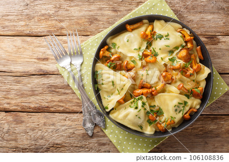 Italian pasta in the shape of a triangle stuffed with chanterelle mushrooms, onions and herbs close-up in a plate. Horizontal top view 106108836