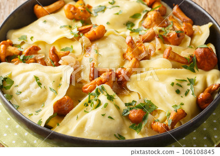 Triangoli Italian pasta in the shape of a triangle with forest mushrooms, onions and herbs close-up in a plate. Horizontal 106108845