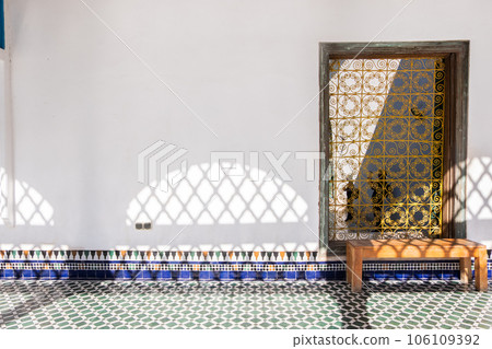 Windows with yellow grate in a white wall with wooden bench and typical Moroccan ceramic on the floor Windows with yellow grate in a white wall with wooden bench and typical Moroccan ceramic on the floor 106109392