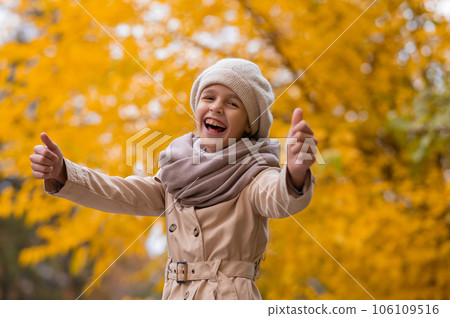 Happy caucasian girl in a beige coat and beret walks in the park in autumn. Happy caucasian girl in a beige coat and beret walks in the park in autumn. 106109516
