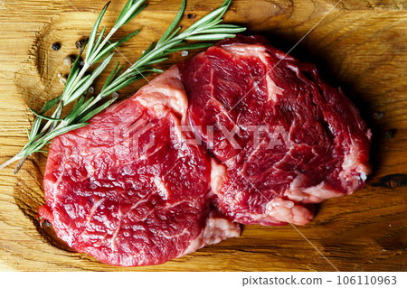 Raw organic beef meat with rosemary, seasonings, salt and red pepper  on wooden cutting board 106110963